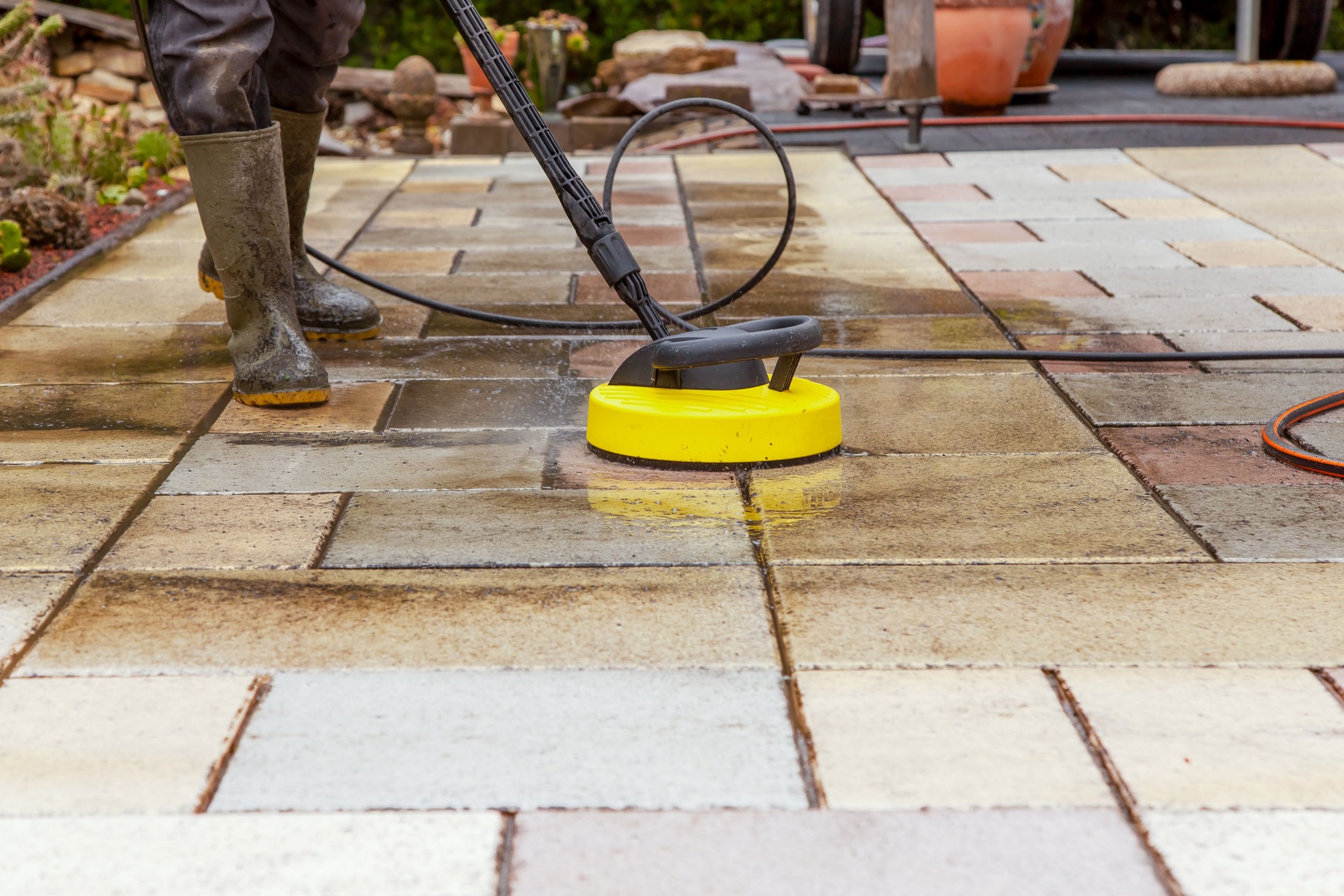 Cleaning stone slabs on patio with the high-pressure cleaner.